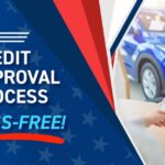 Couple smiling with dealership representative discussing vehicle financing and credit approval process.